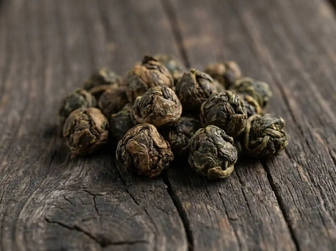 Mains d'artisan roulant des perles de thé oolong sur une table en bois brut