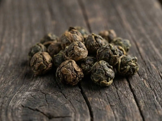 Mains d'artisan roulant des perles de thé oolong sur une table en bois brut